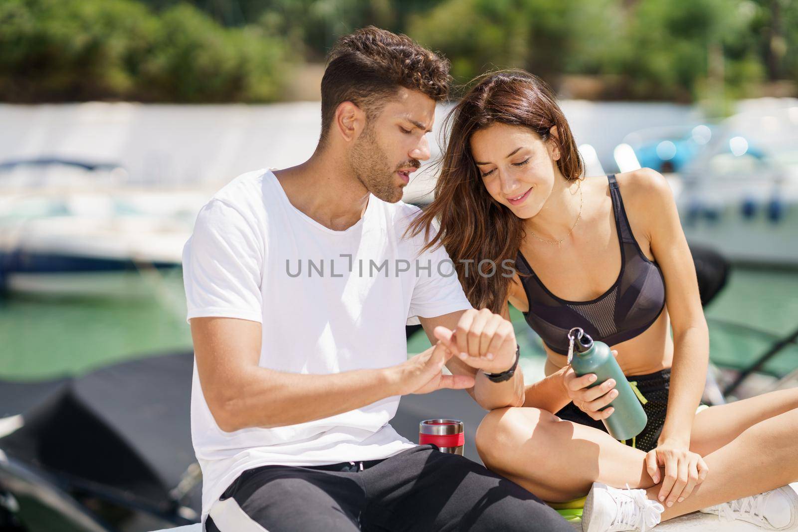 Man showing his marks to an athletic woman on a sports watch after exercise. People using smartwatch.