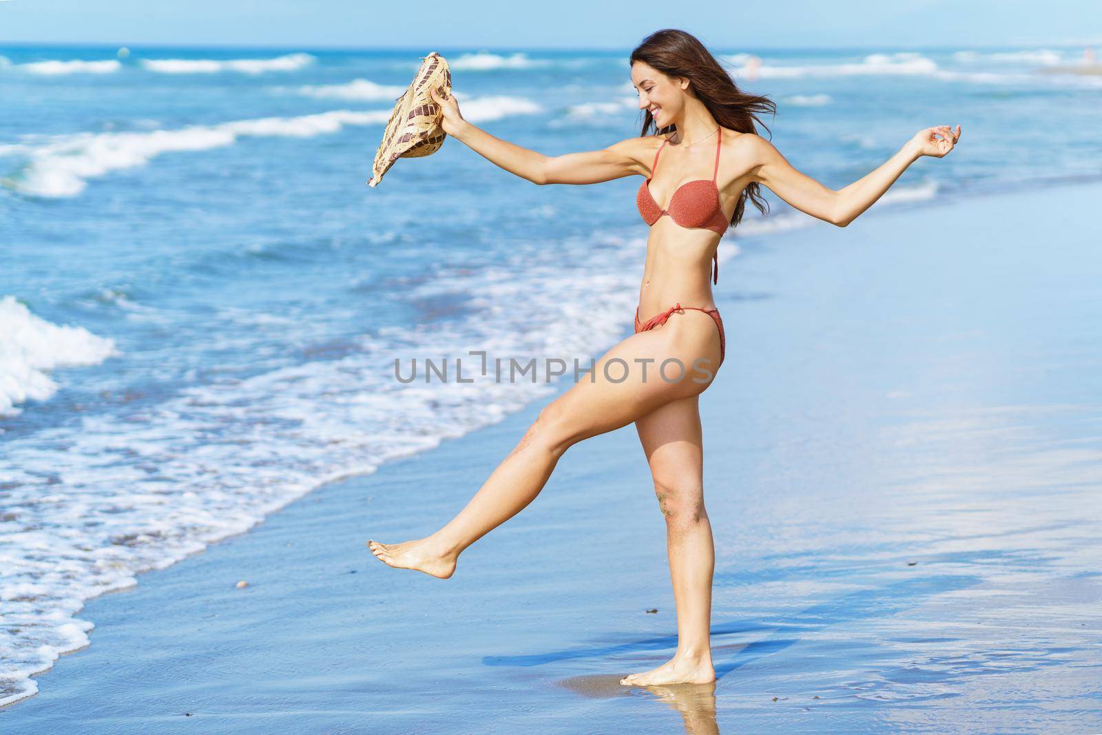 Woman in swimwear and sunhat, enjoying the beach on her holiday. by javiindy