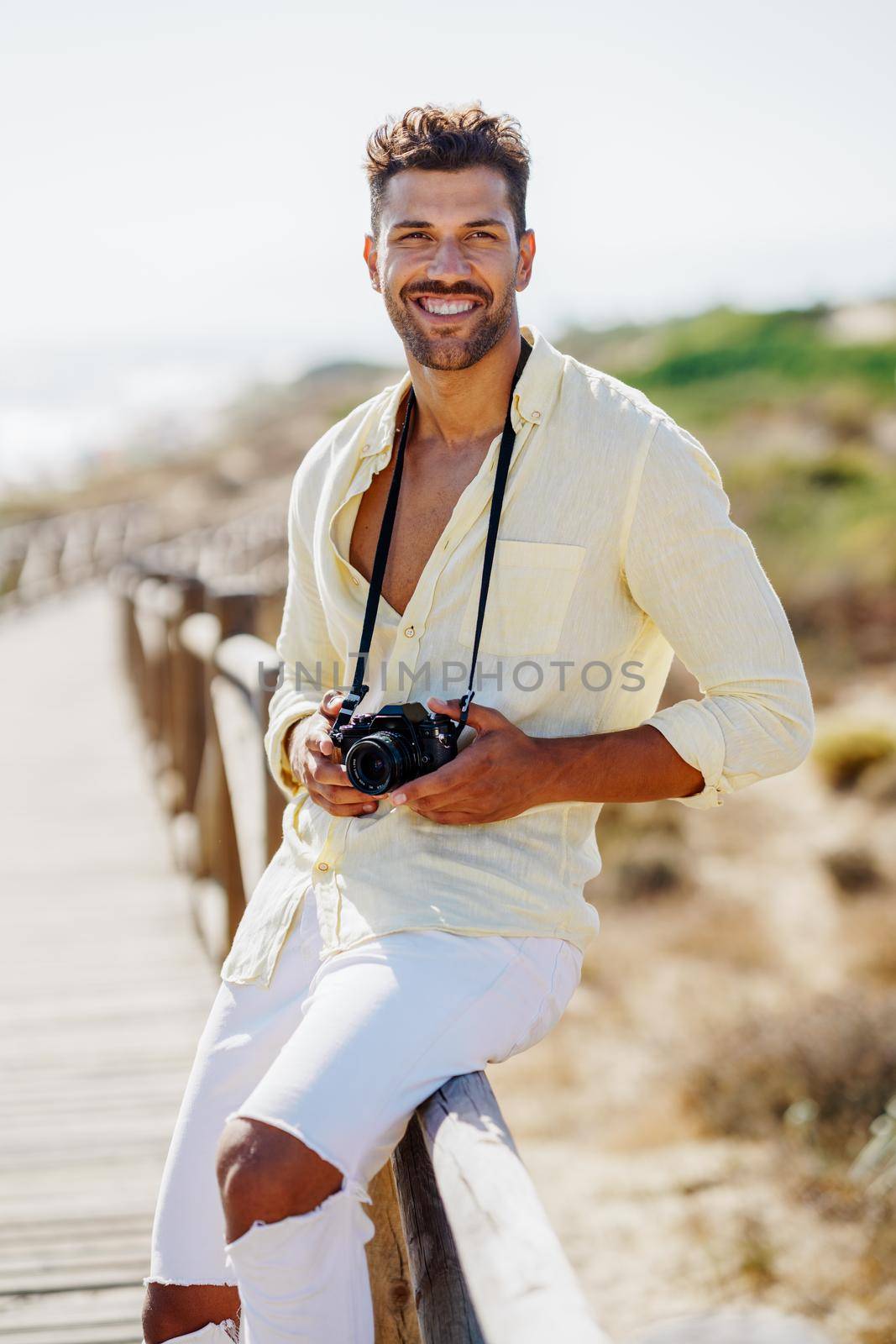 Smiling man photographing in a coastal area with an SLR camera