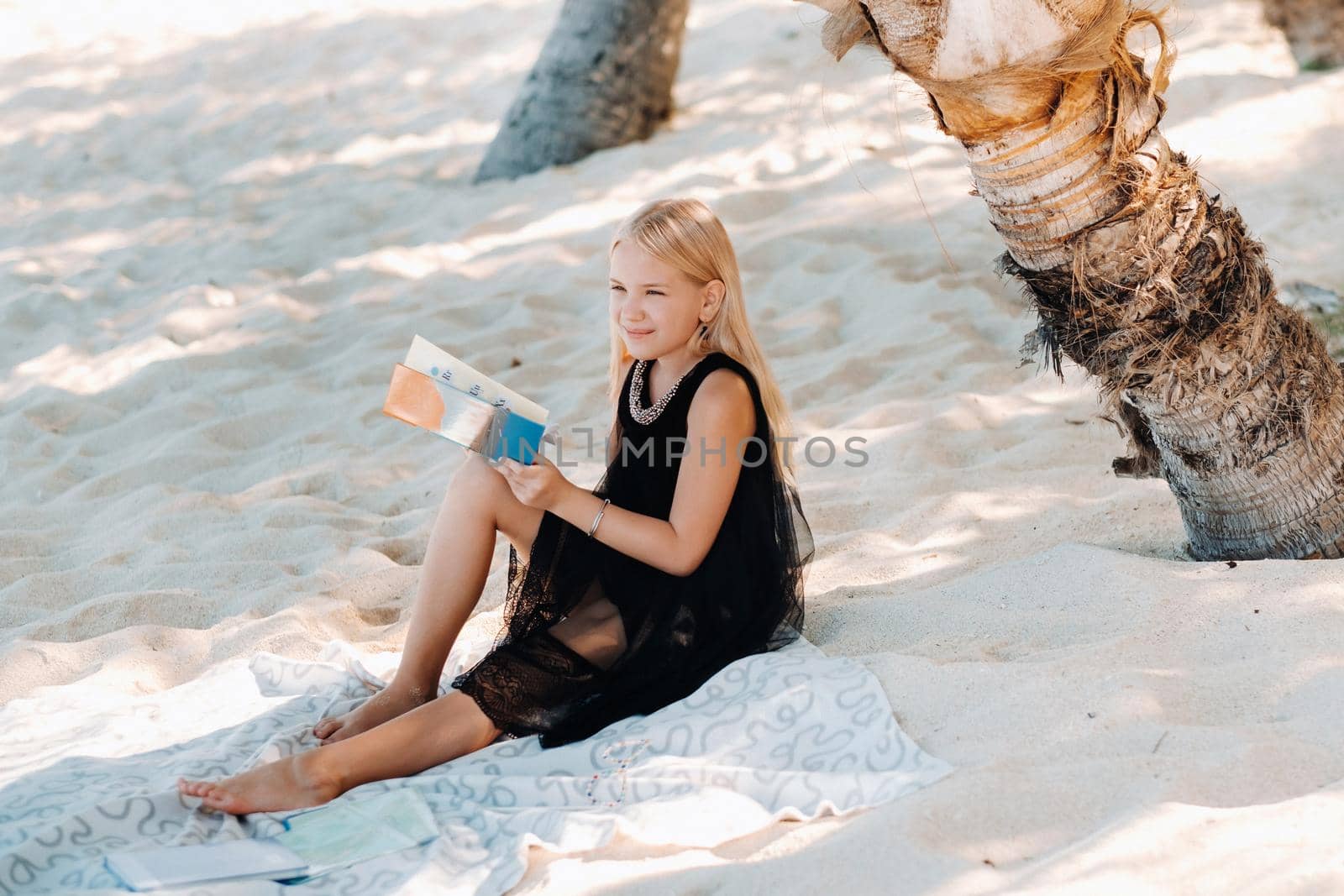 a little girl sits and enjoys the tropical beach of Le Morne in Mauritius.A girl reads a book on the beach in Mauritius by Lobachad