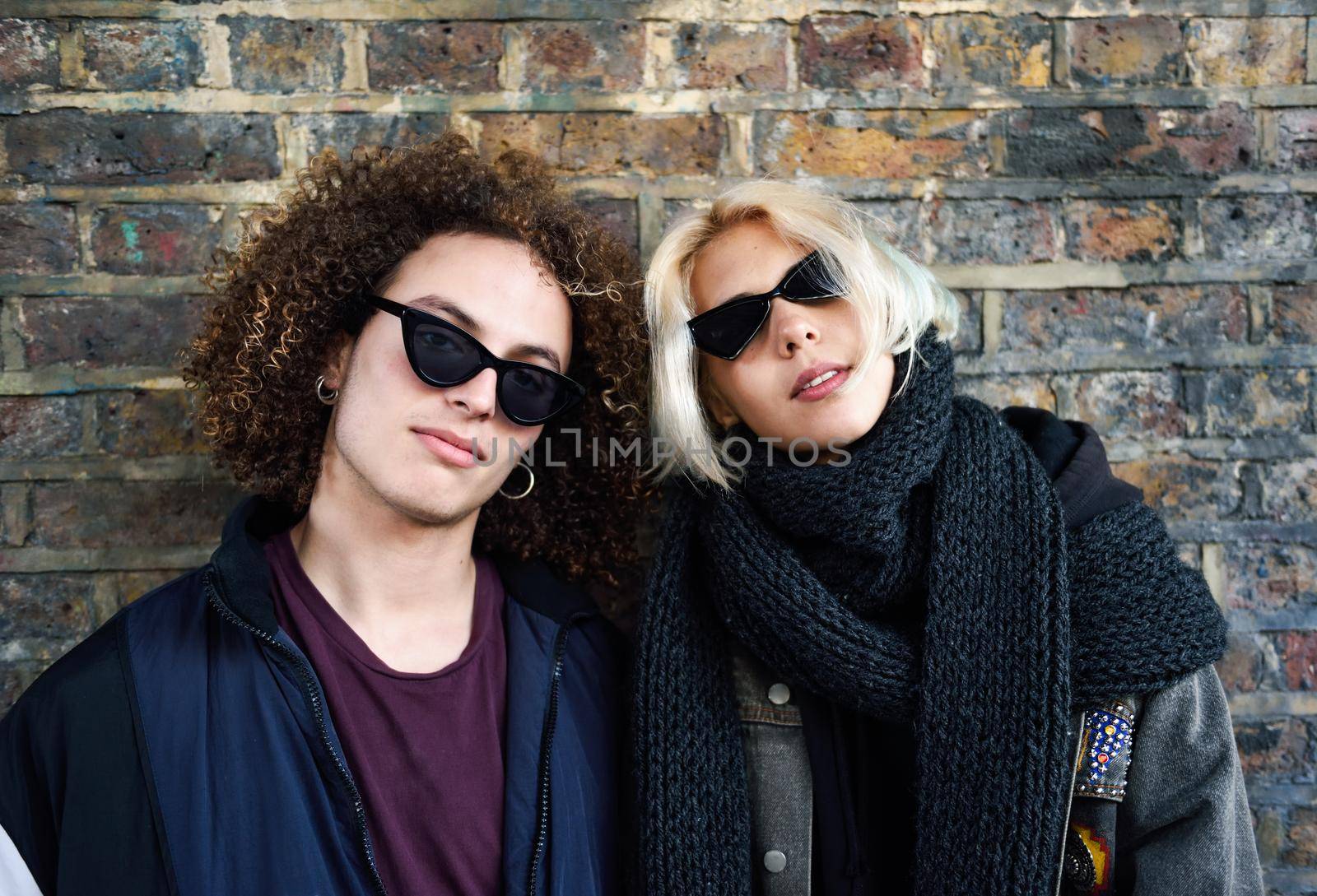 Young couple enjoying Camden town in front of a brick wall typical of London, UK