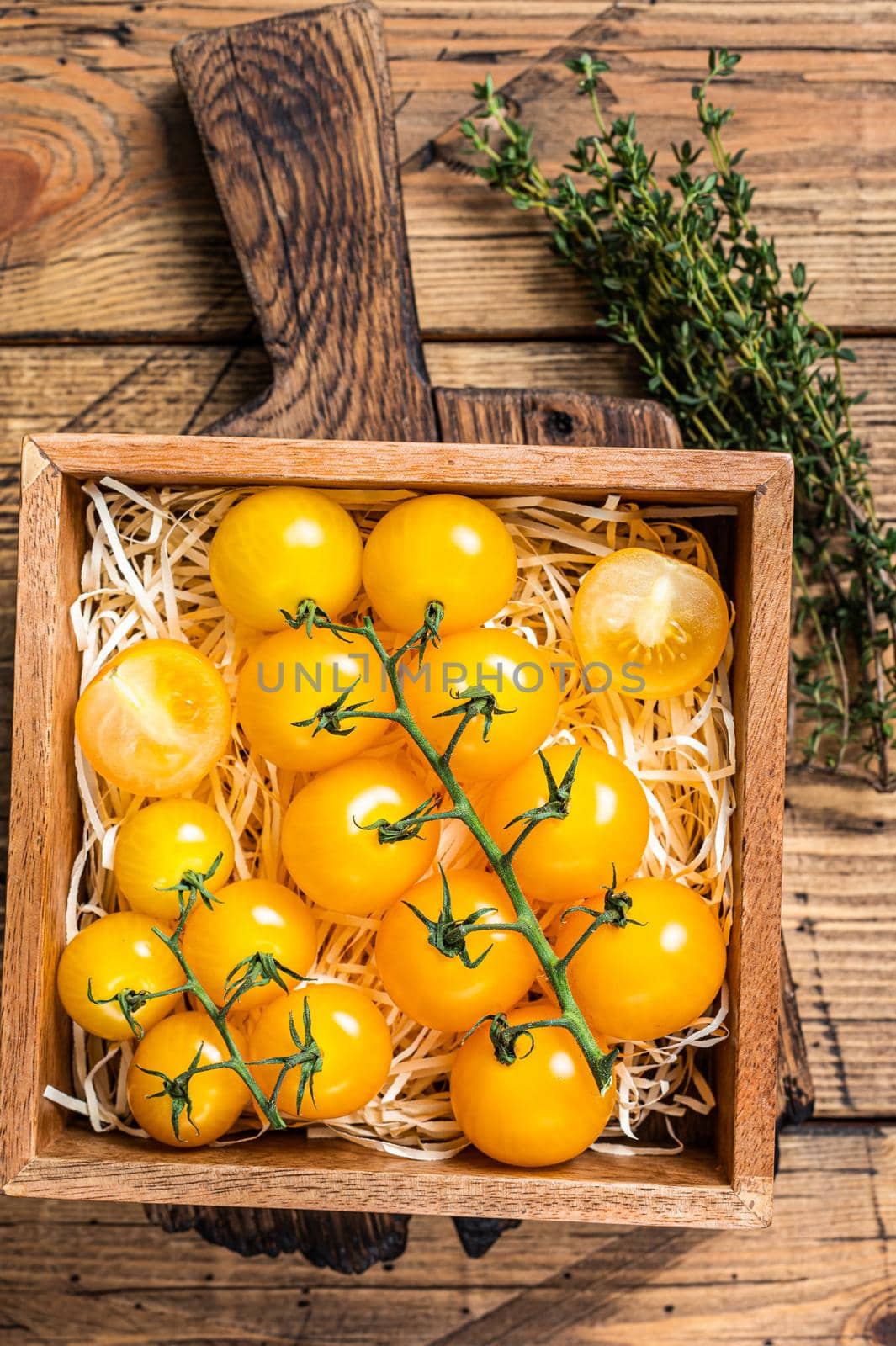 Box with yellow cherry tomato. wooden background. Top view.