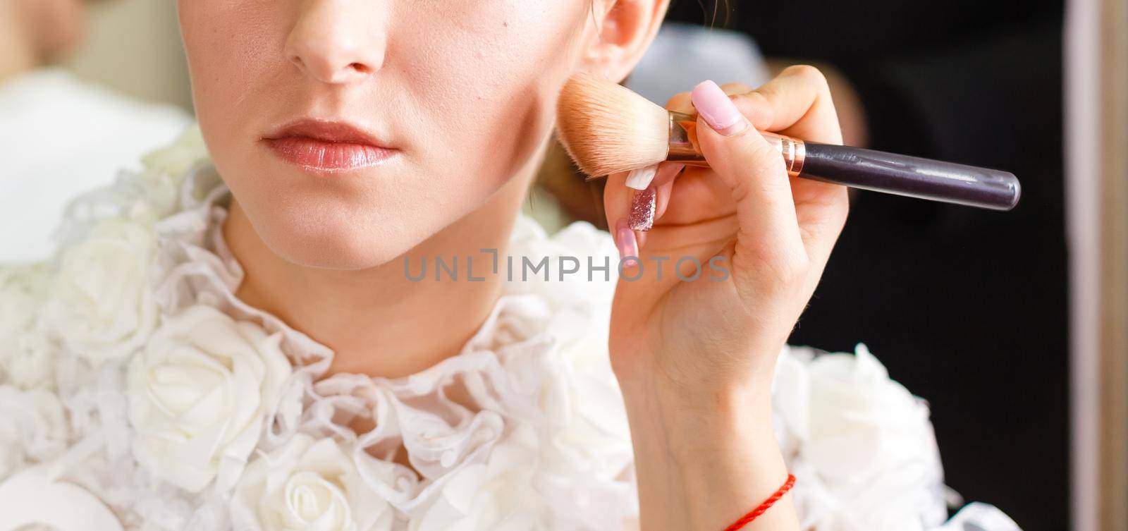 Portrait of beautiful woman holding make-up brush. Professional makeup. Applying rouge over the face by Andelov13