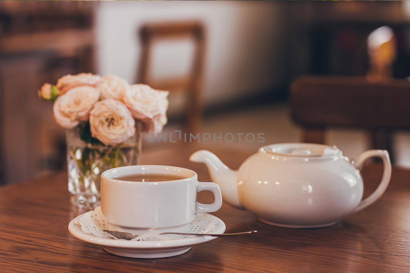 Beautiful fresh roses near a cup of tea and a in pastel tones romantic mood.