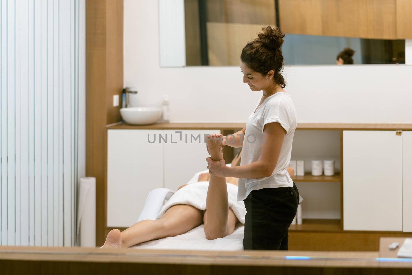 Middle-aged woman having a leg massage in a beauty salon. by javiindy