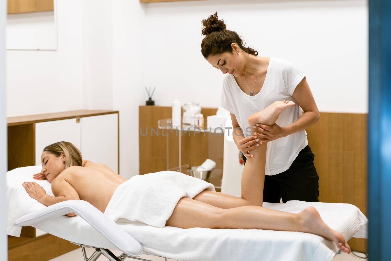 Middle-aged woman having a leg massage in a beauty salon. Body care treatment in a beauty centre.