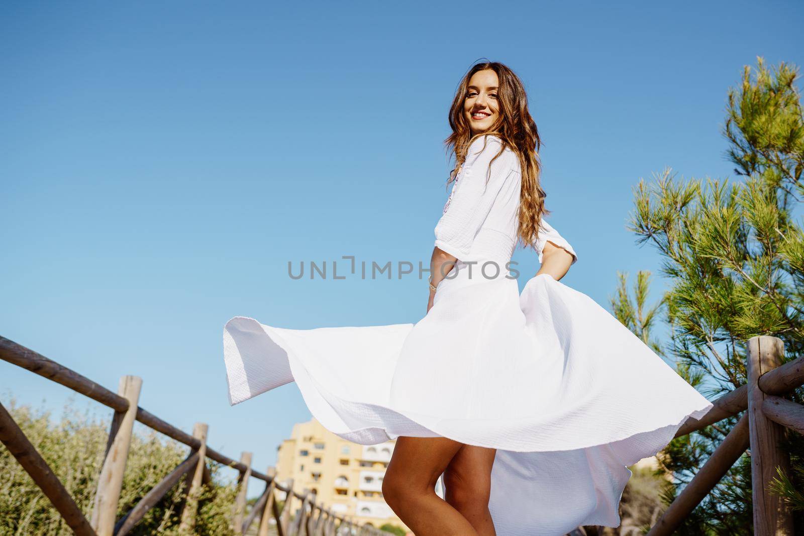 Young woman wearing a beautiful white dress enjoying a natural environment. by javiindy