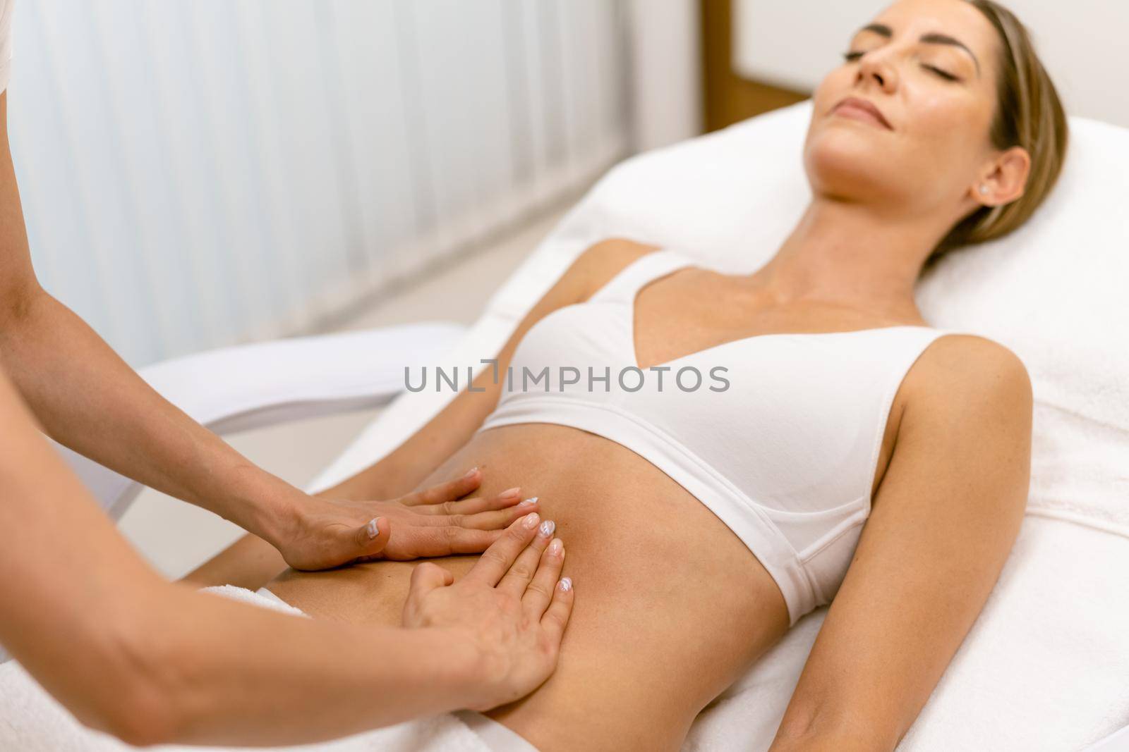 Middle-aged woman having a belly massage in a beauty salon. by javiindy