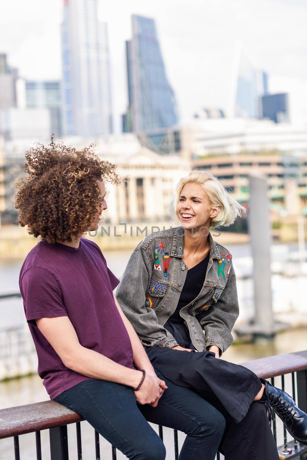 Happy couple talking sitting near River Thames, London. UK