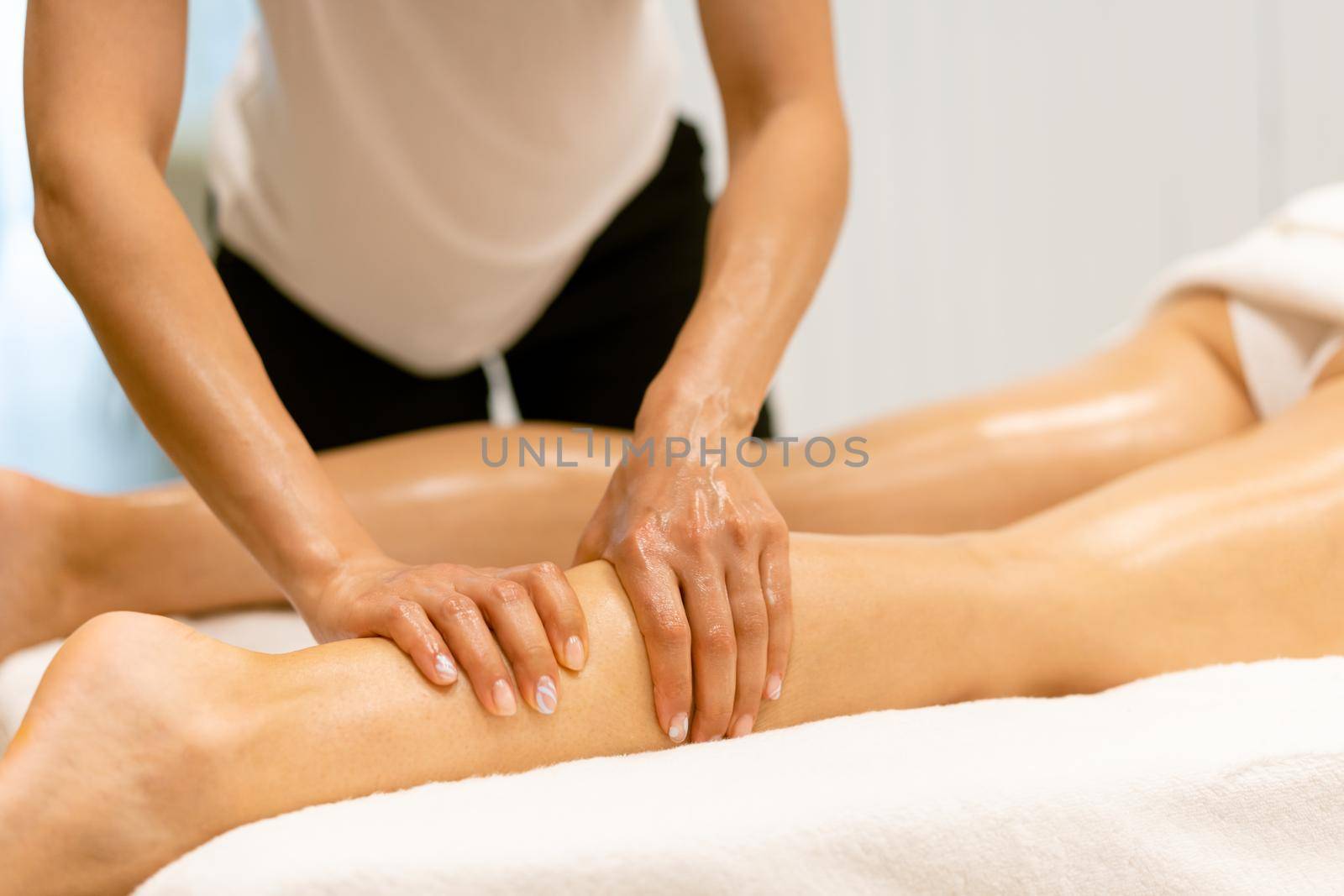 Beauty salon professional pouring oil from a massage candle on the back of his patient. by javiindy