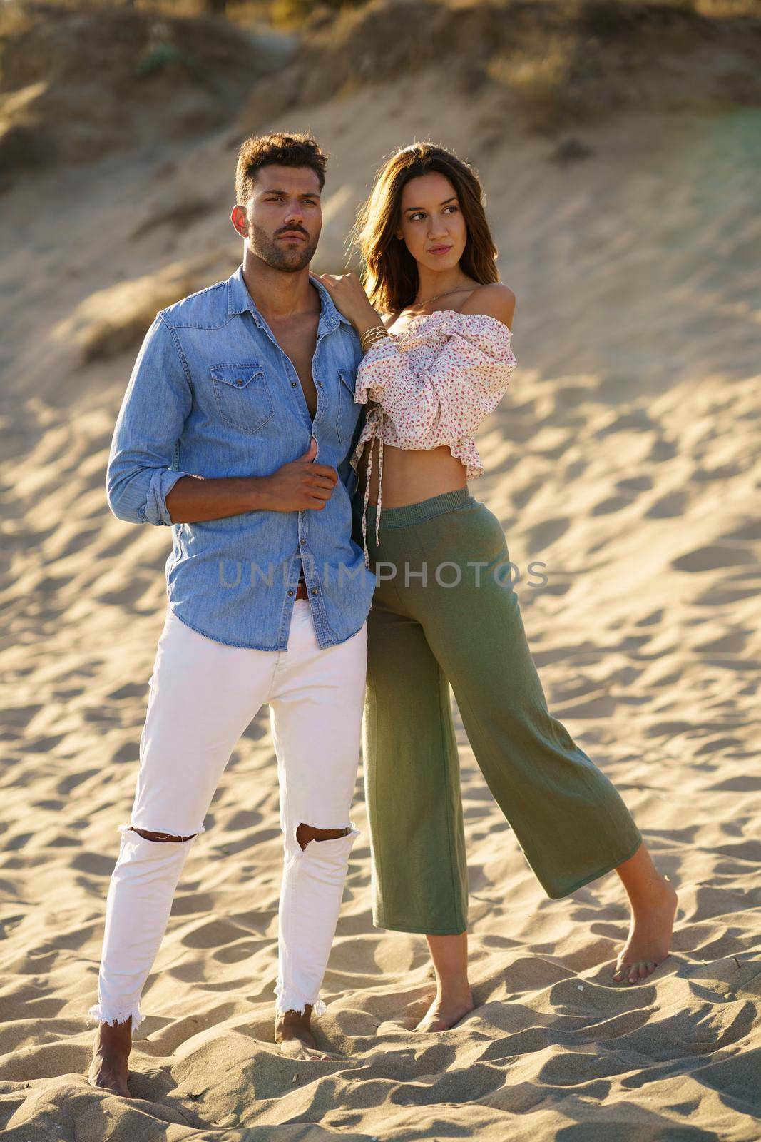 Young couple standing on the sand of the beach by javiindy