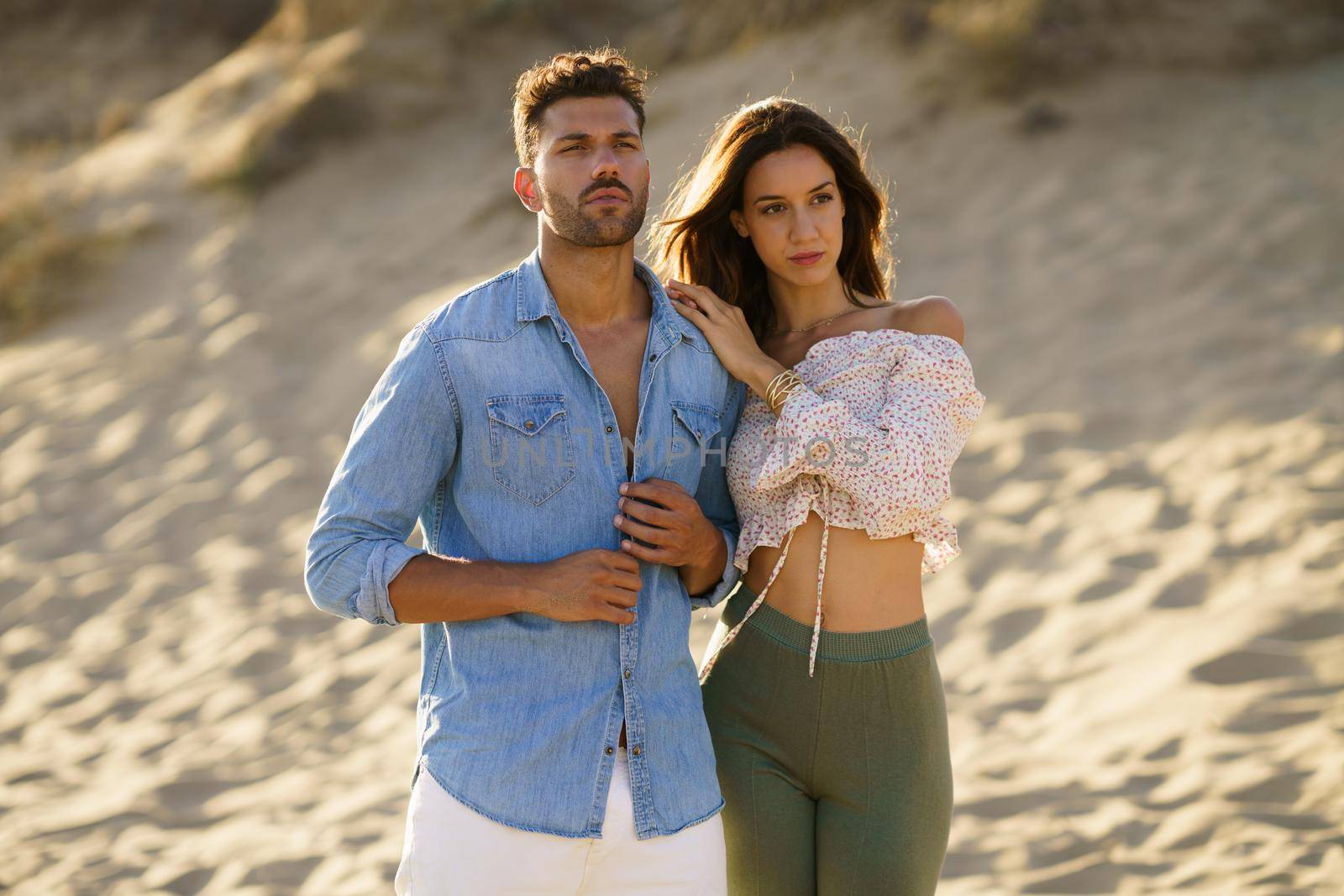 Young couple standing on the sand of the beach wearing casual clothes.