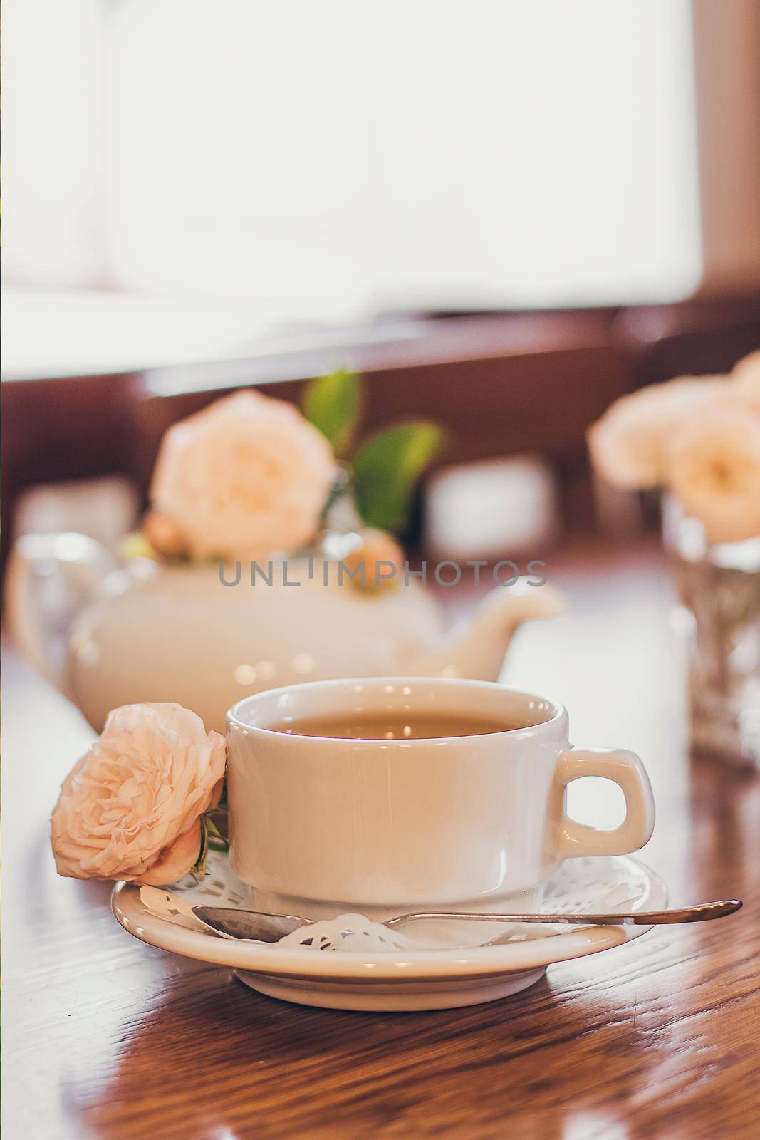 Beautiful fresh roses near a cup of tea and a in pastel tones romantic mood.