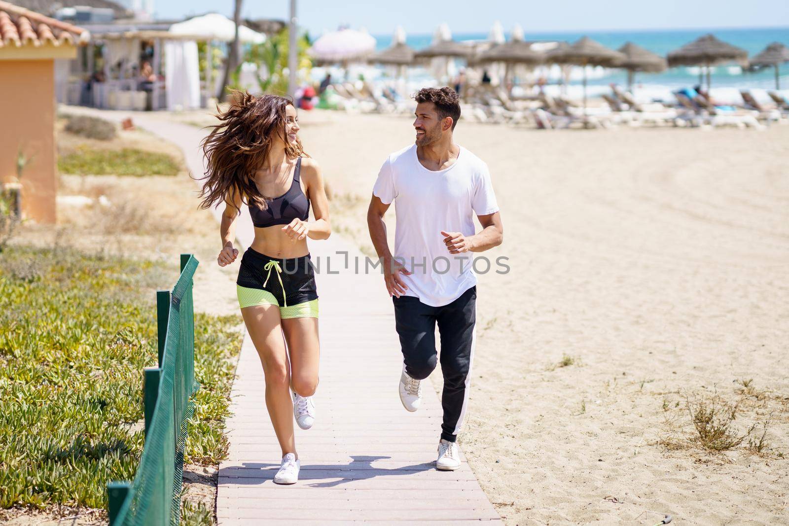 Young couple training running on the beach by javiindy