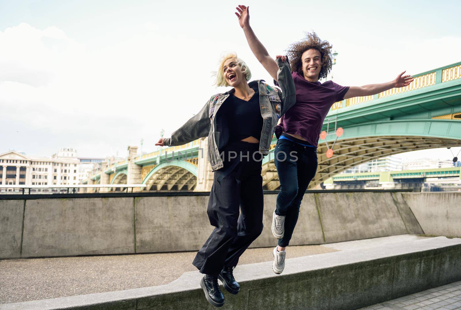 Funny couple junping near the Southwark bridge over River Thames, London. UK