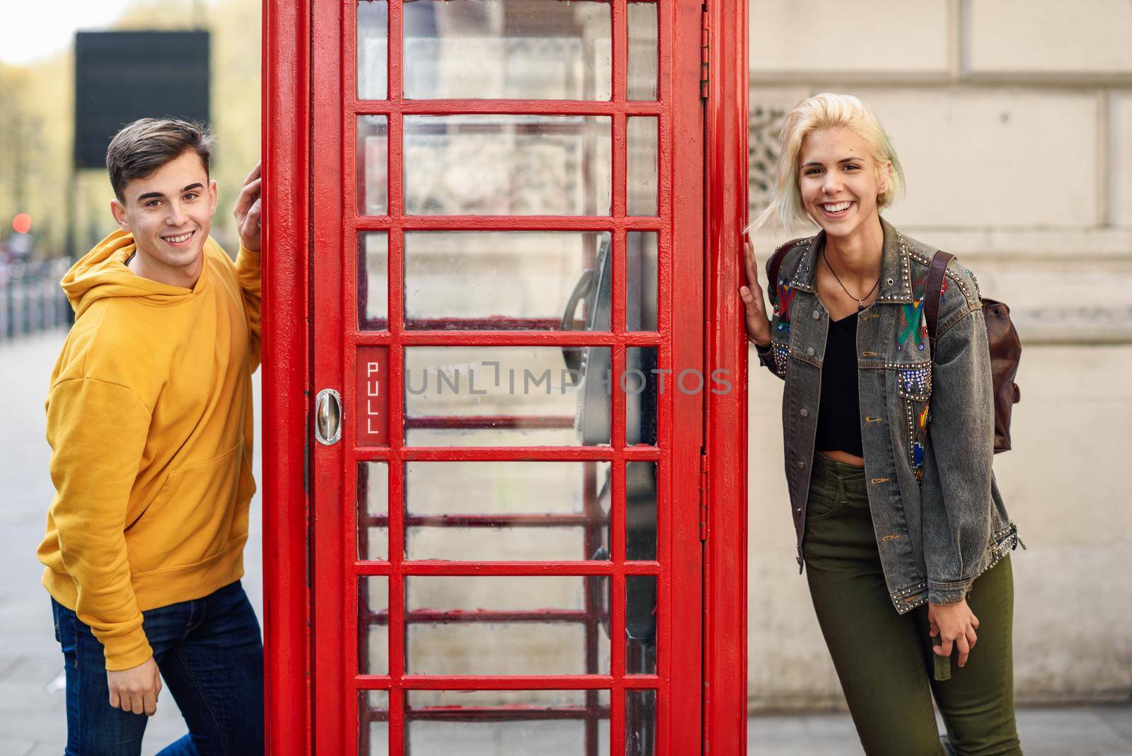 Young couple of friends near a classic British red phone booth by javiindy