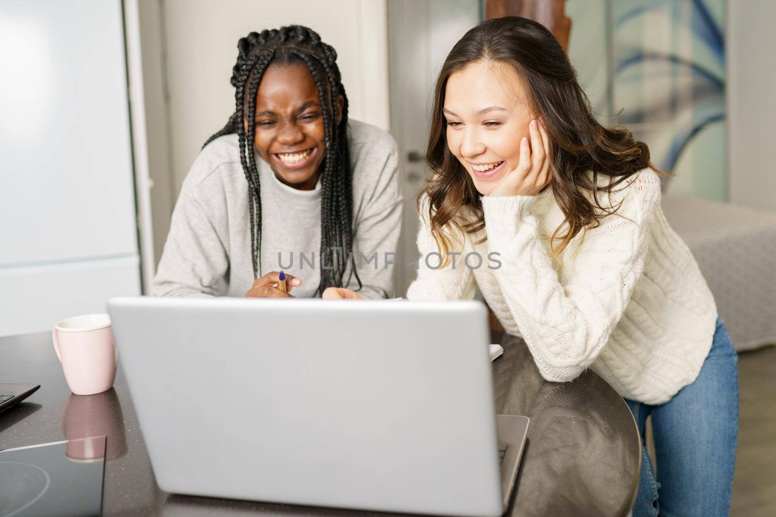 Two college girls studying together at home with laptops while drinking coffee by javiindy