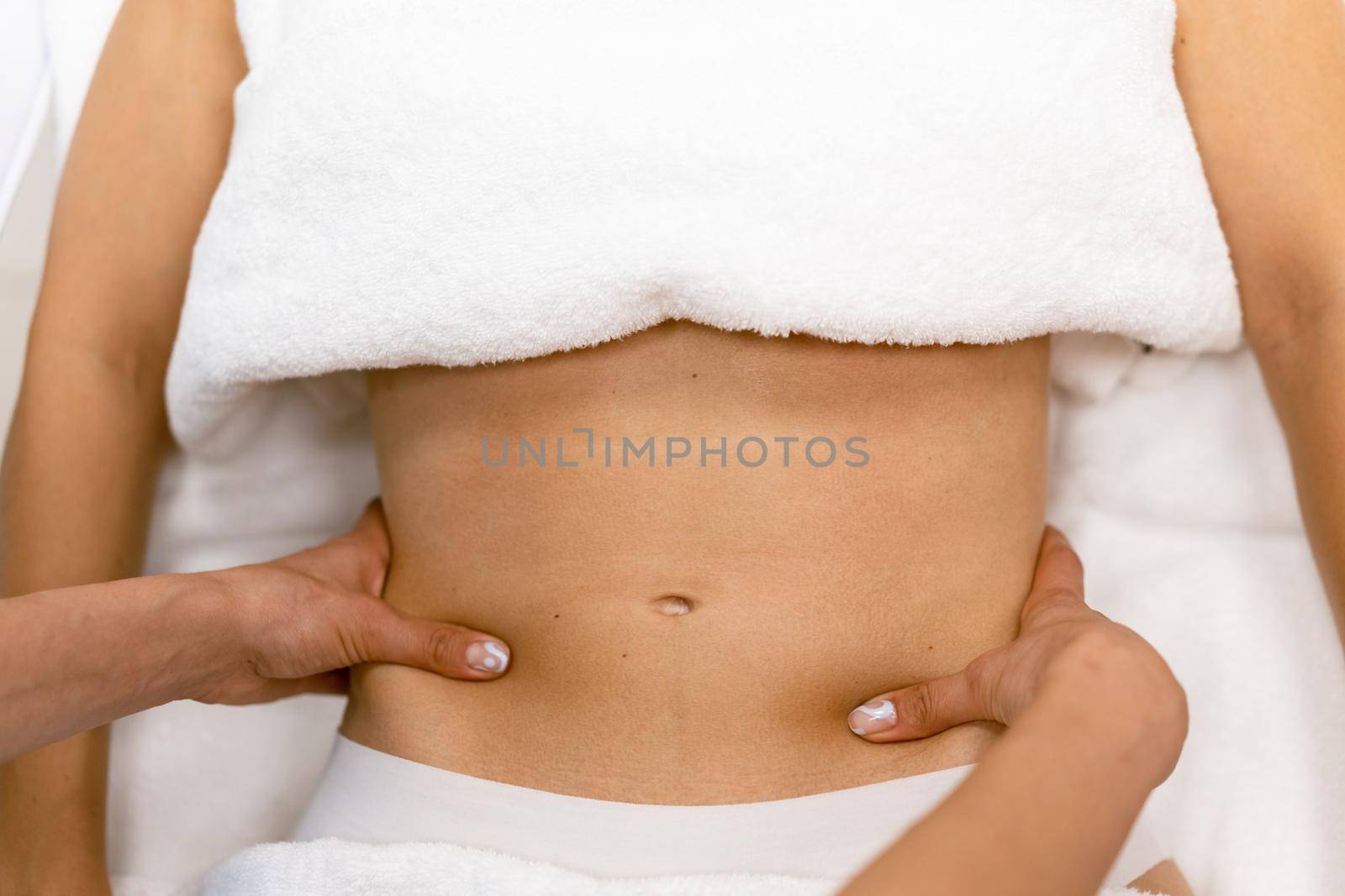 Middle-aged woman having a belly massage in a beauty salon. Body care treatment in a beauty centre.