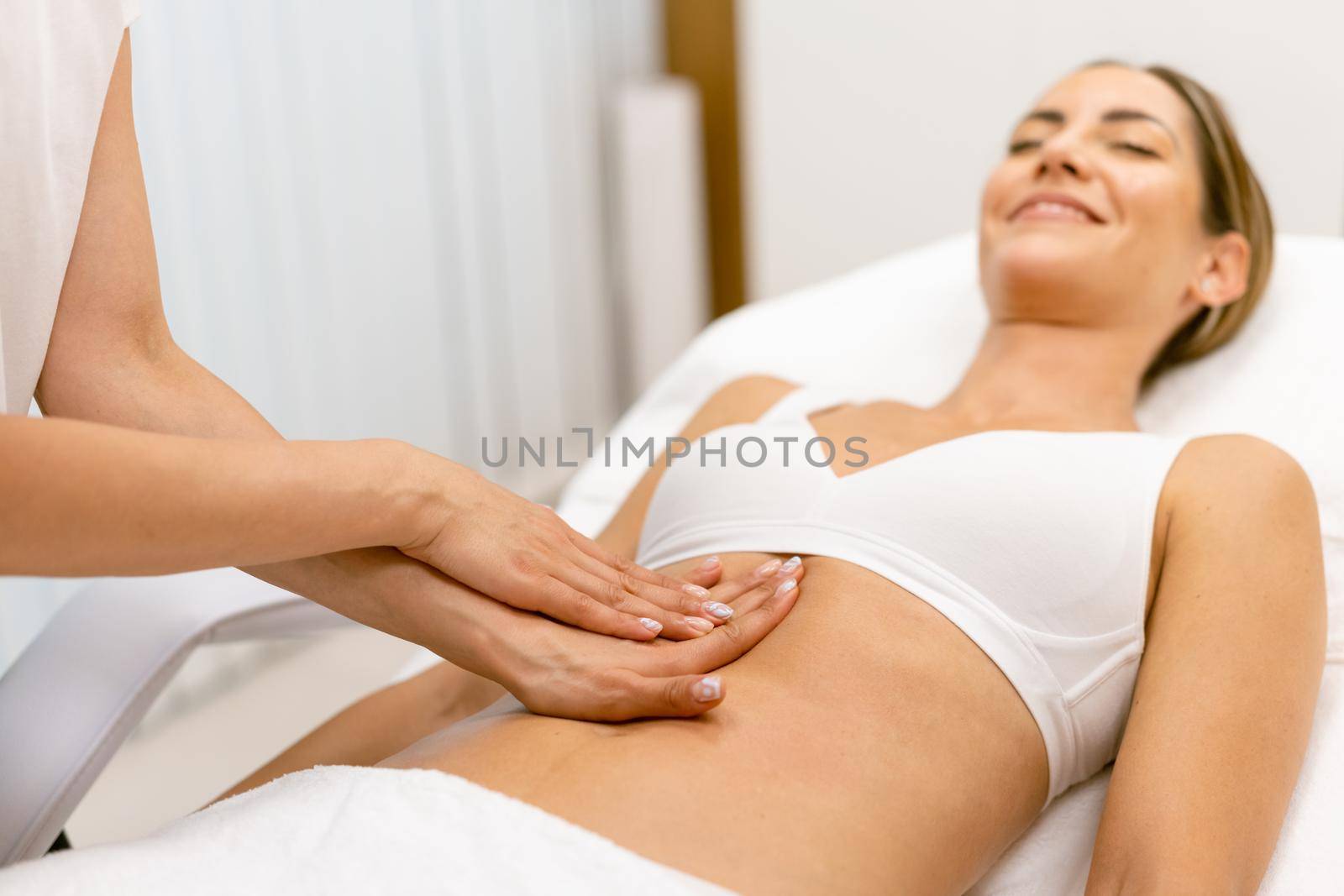 Middle-aged woman having a belly massage in a beauty salon. Body care treatment in a beauty centre.