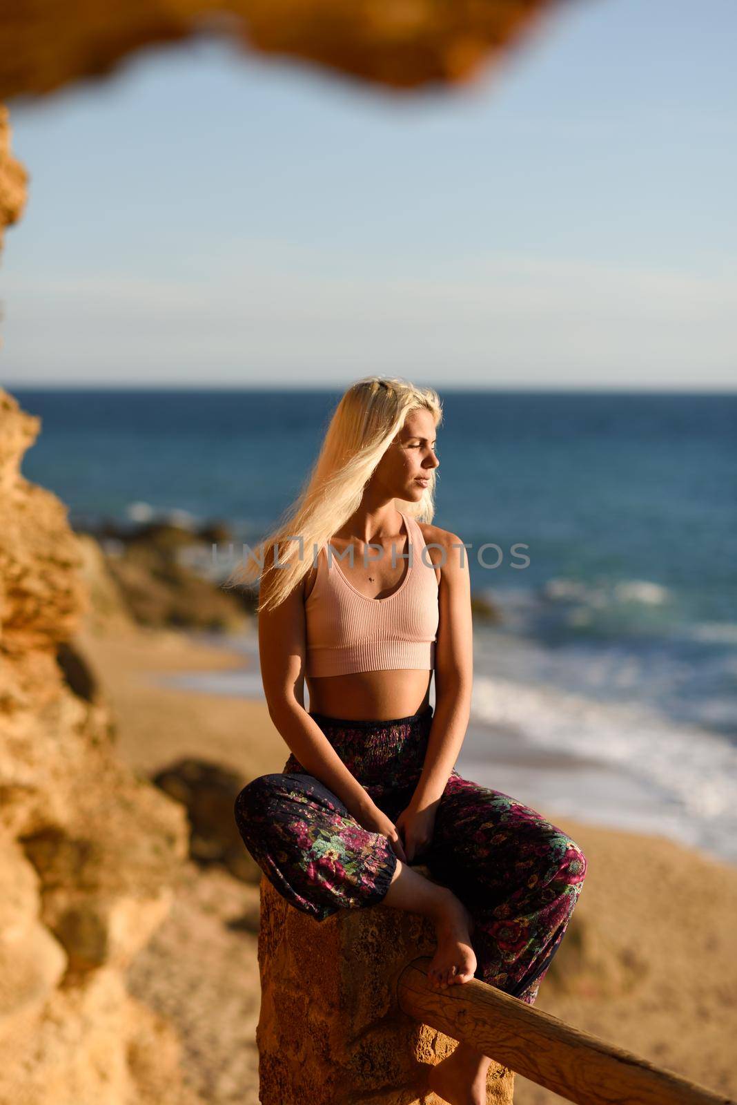 Woman enjoying the sunset on a beautiful beach in Cadiz, Andalusia, Spain. Young female sitting on beautiful stairs looking at the sea with golden light.