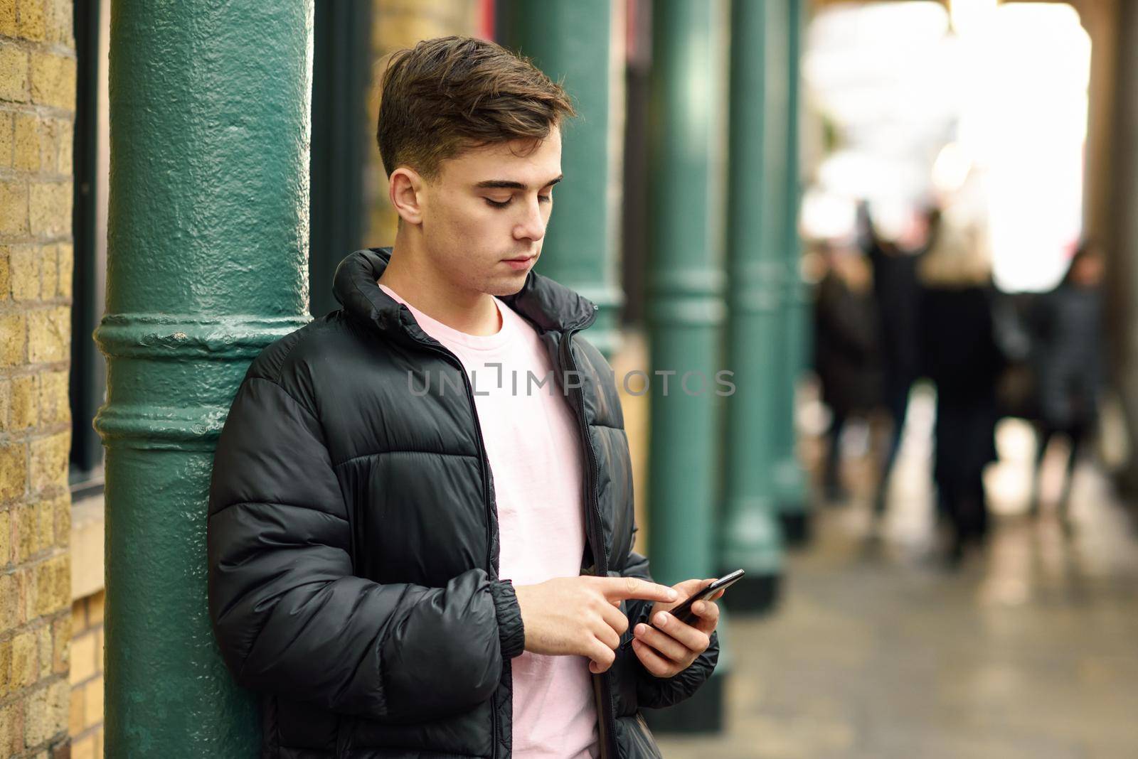 Young urban man using smartphone in urban background in London, UK