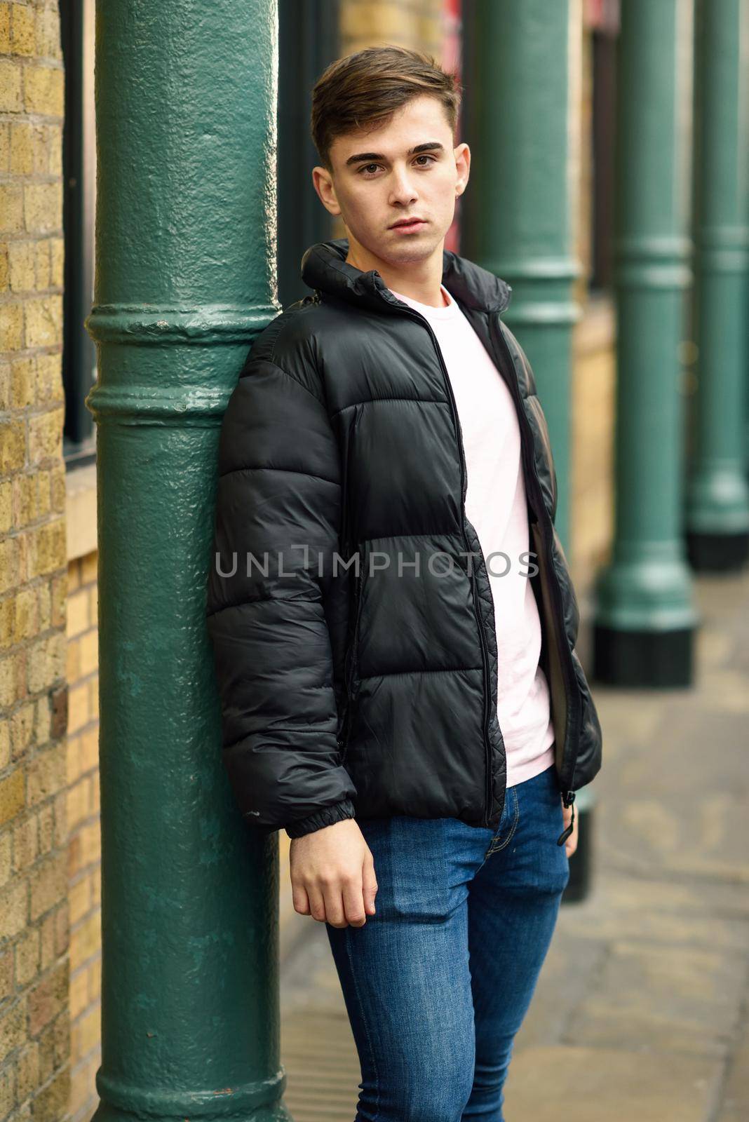 Young man standing in urban background with modern hairstyle. by javiindy