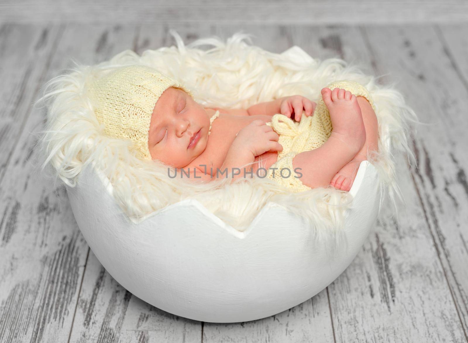 sweet newborn baby in hat and panties sleeping on round bed, top view