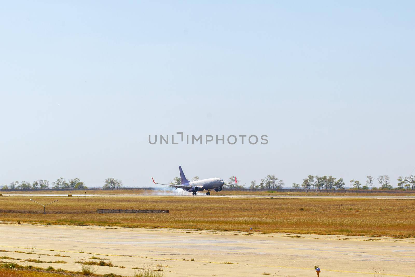Passenger plane taking off from runway at airport on sunny day. by Fabrikasimf