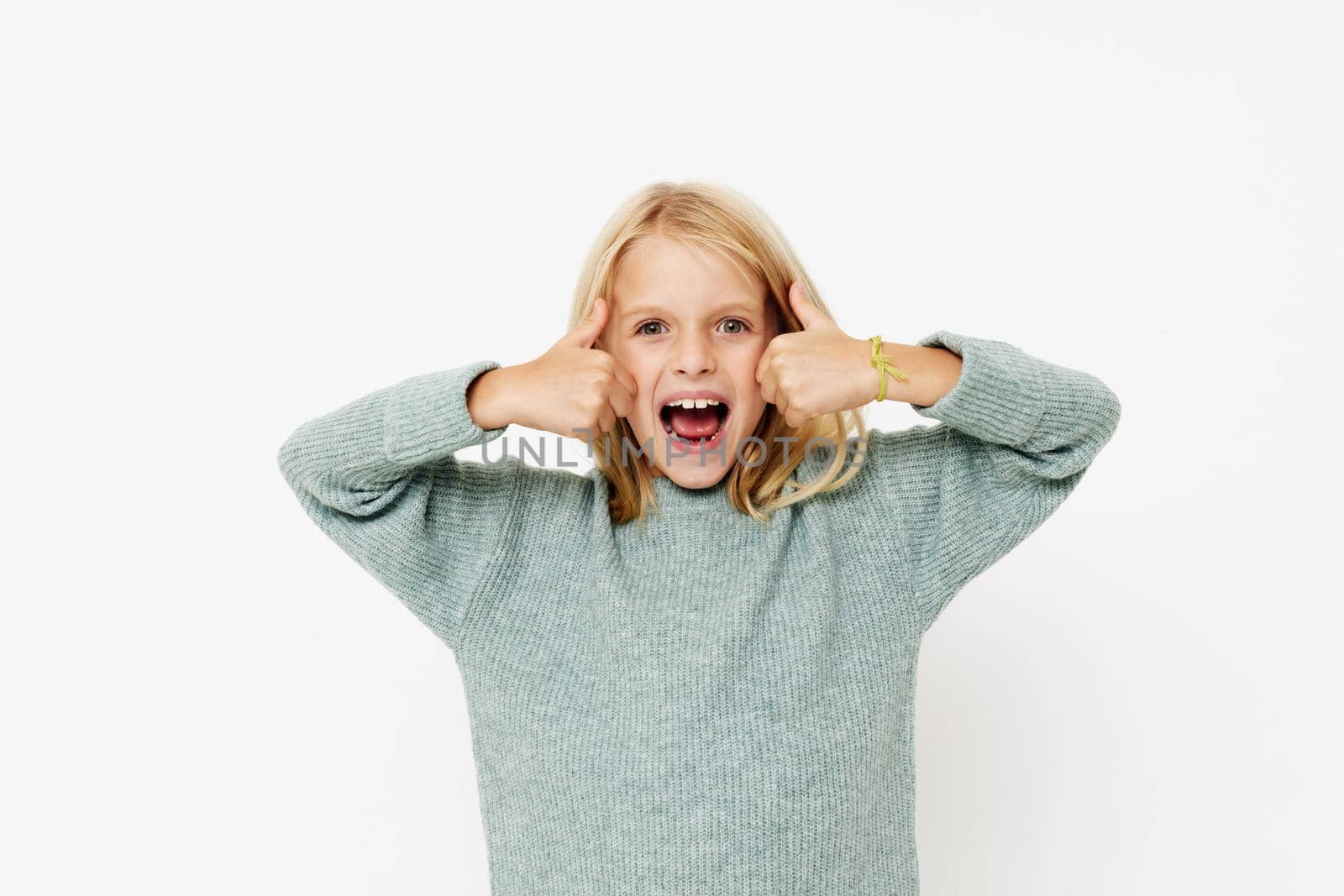 emotional girl in a sweater, grimaces on a light background by SHOTPRIME