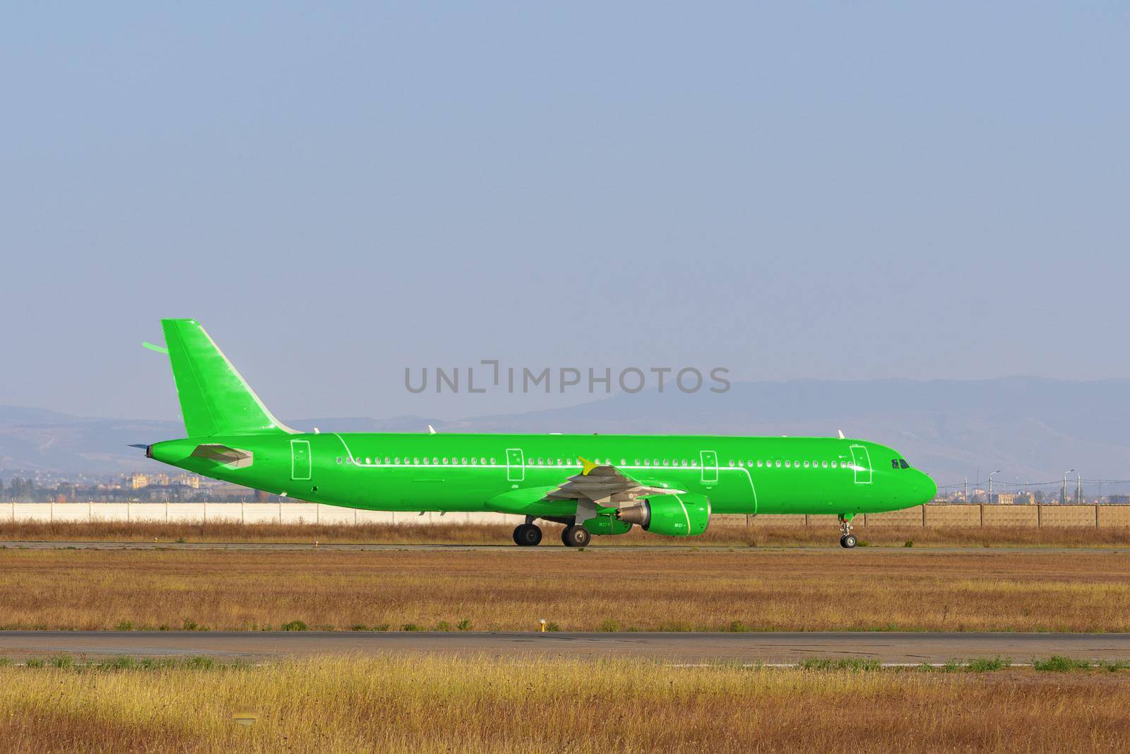 Green passenger airplane at the airport on sunny day by Fabrikasimf