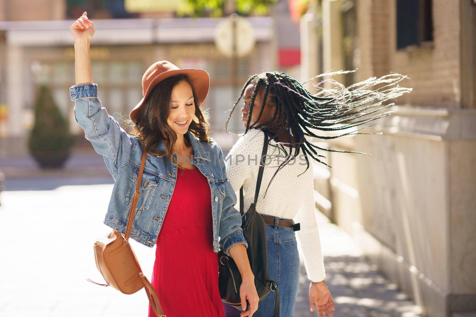 Two female dancing together on the street. Multiethnic friends. by javiindy