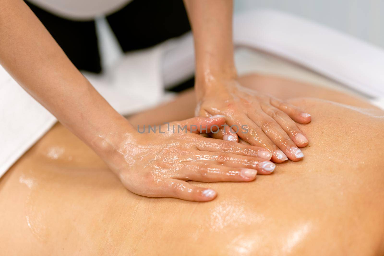 Woman receiving a back massage with massage candle oil. Body care treatment in a beauty centre.