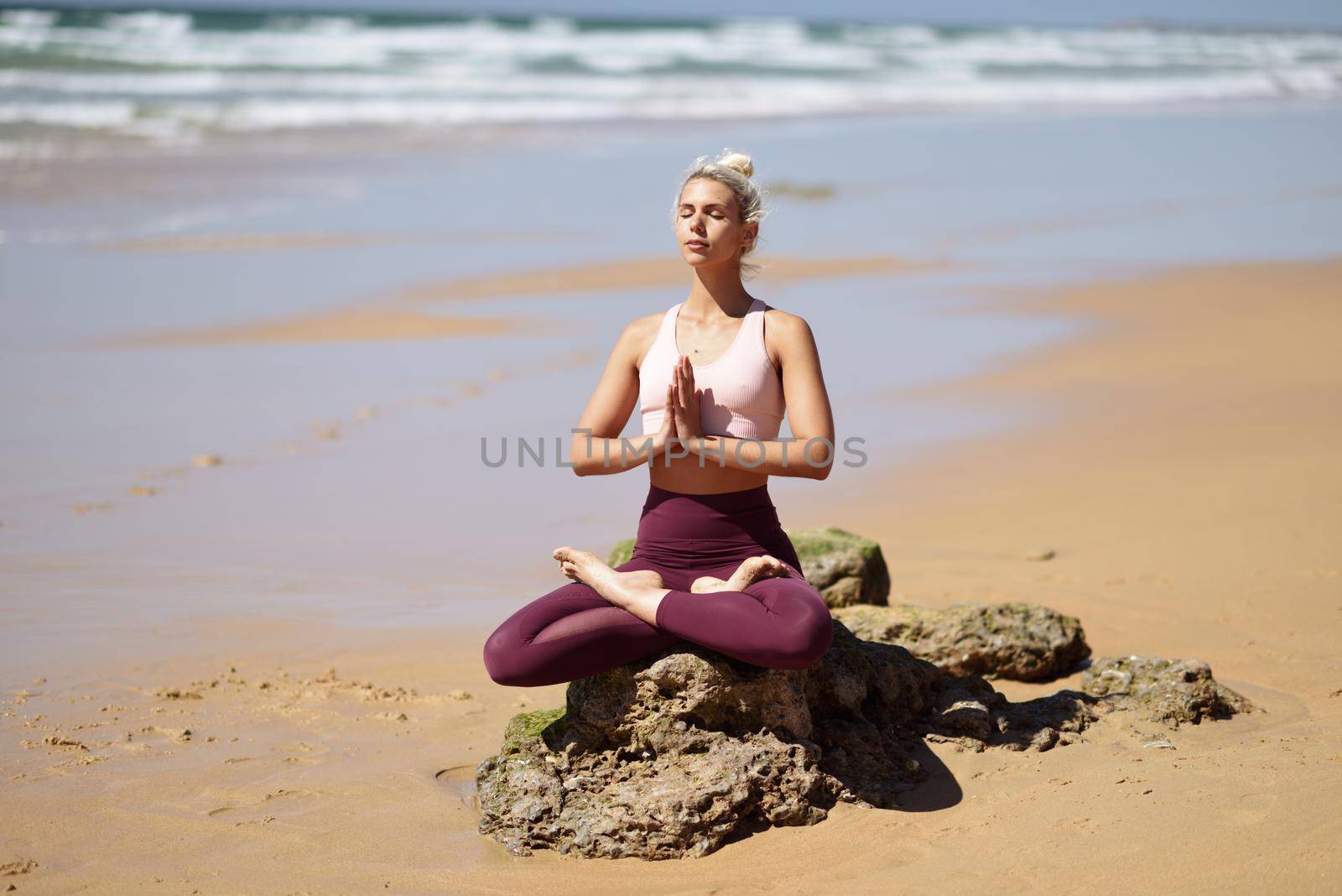 Caucasian woman practicing yoga at seashore. Young female doing lotus pose in the beach in Cadiz, Andalusia, Spain.