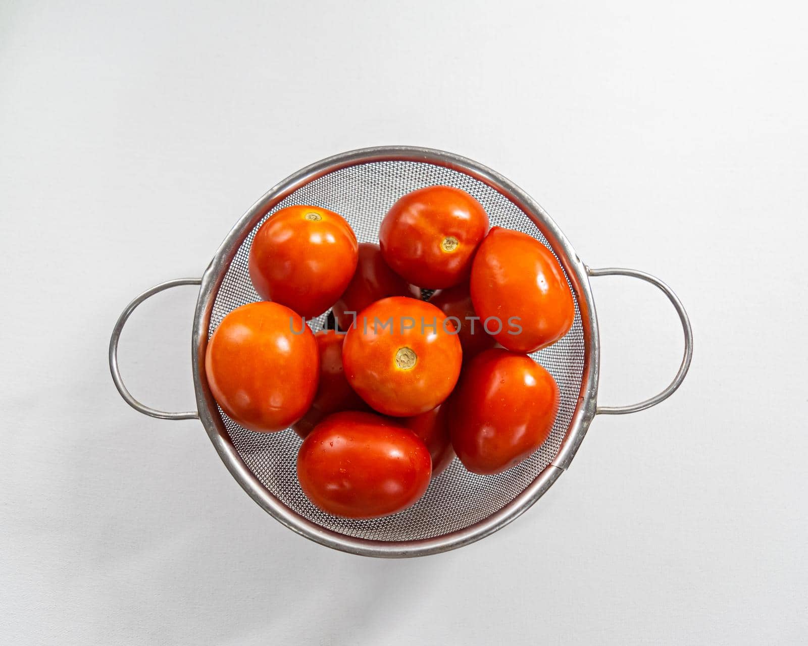 Close up image of Fresh red tomatoes washed with water and kept in a net pot with plain white background. by lalam