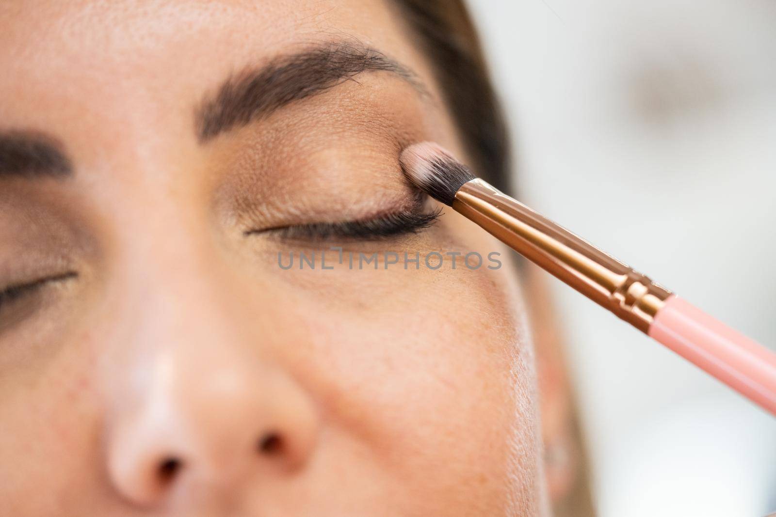 Close-up of a make-up artist applying eye shadow to her client. by javiindy