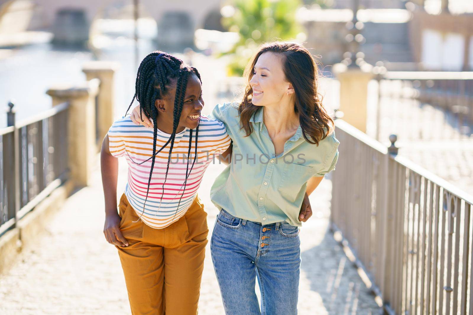 Two Multiethnic women walking together on the street. by javiindy