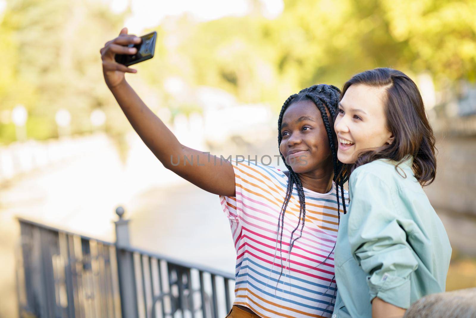 Two multiethnic women making selfie with a smartphone outdoors.