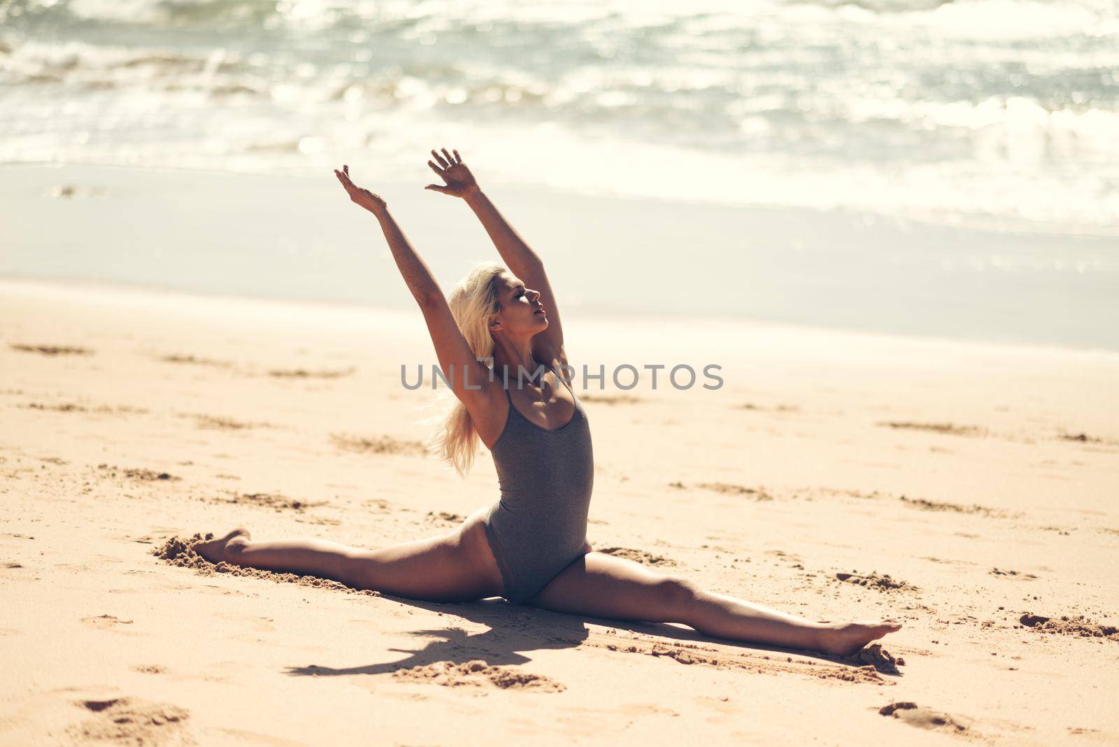 Caucasian blonde woman practicing yoga in the beach by javiindy