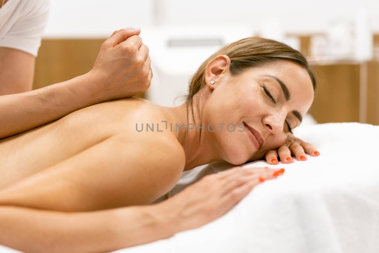 Middle-aged woman having a back massage in a beauty salon. Body care treatment in a beauty centre.