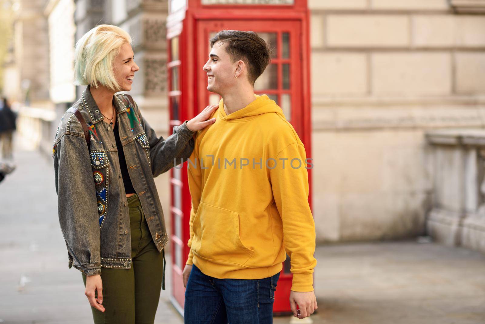 Young couple of friends near a classic British red phone booth by javiindy