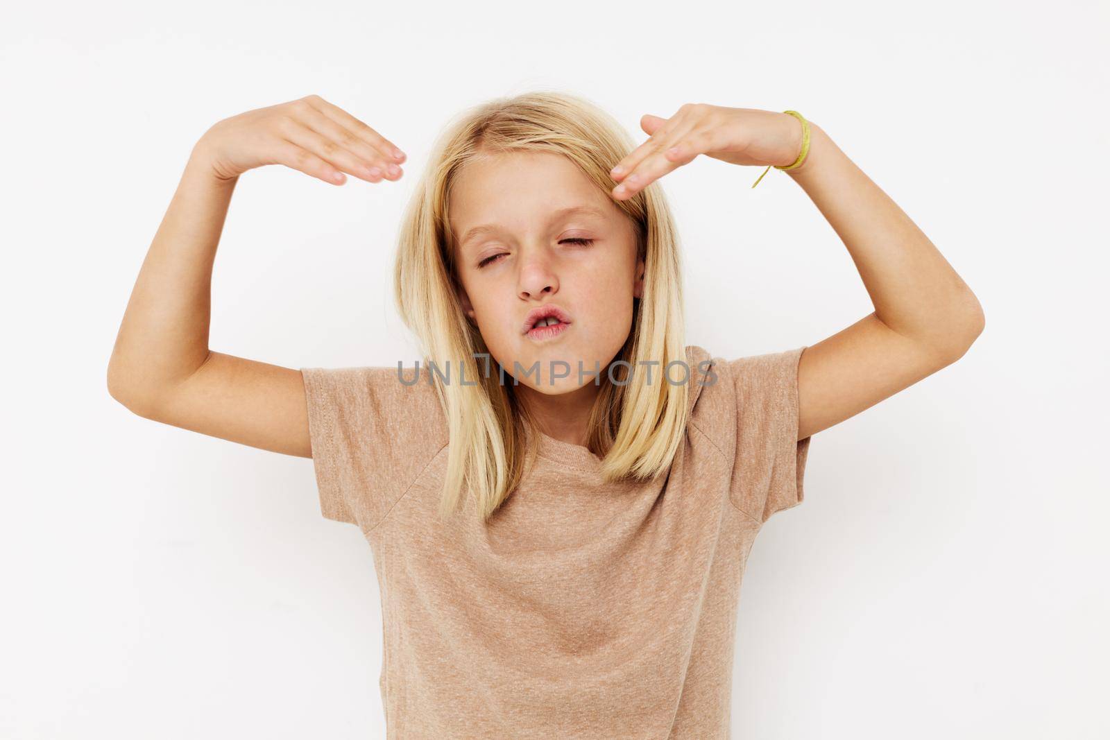 Positive little girl in a beige t-shirt isolated background. High quality photo