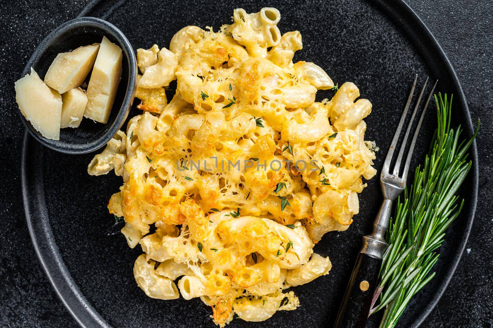 Baked Macaroni Mac and cheese American dish with Cheddar cheese sauce. Black background. Top view by Composter