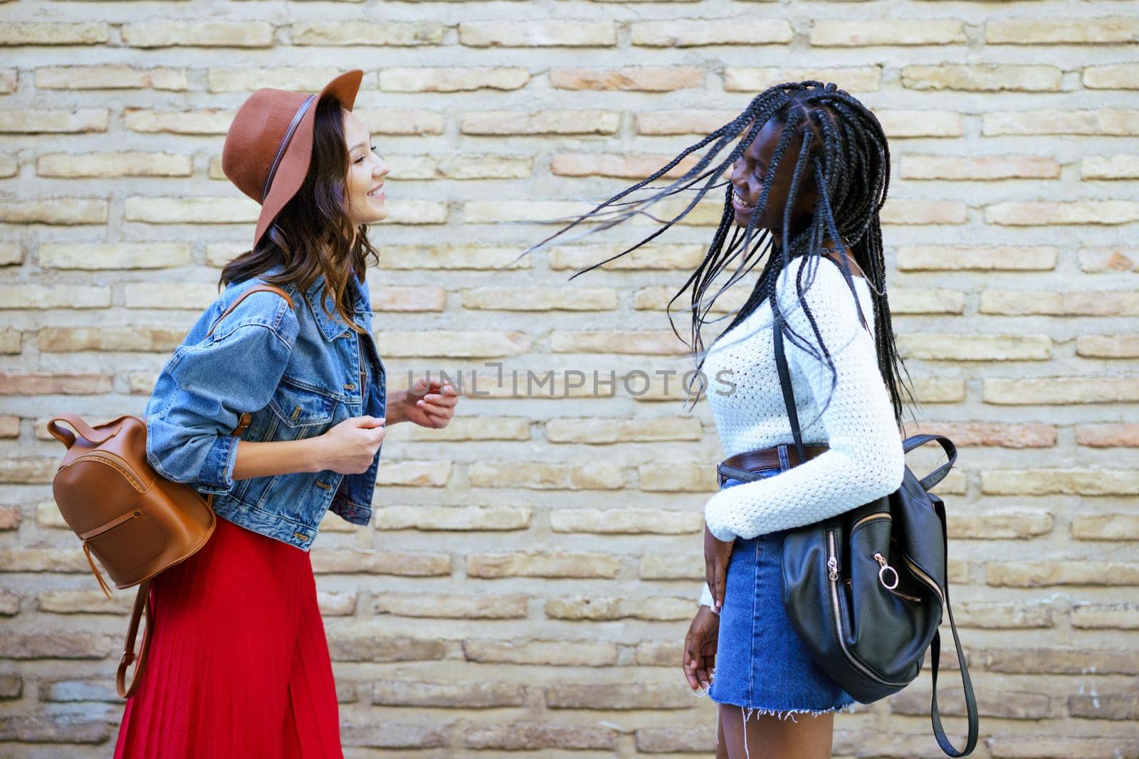 Two female friends having fun together on the street. Multiethnic friends. by javiindy