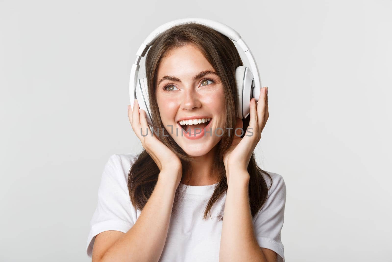 Close-up of beautiful happy girl smiling, enjoying listening music in wireless headphones.