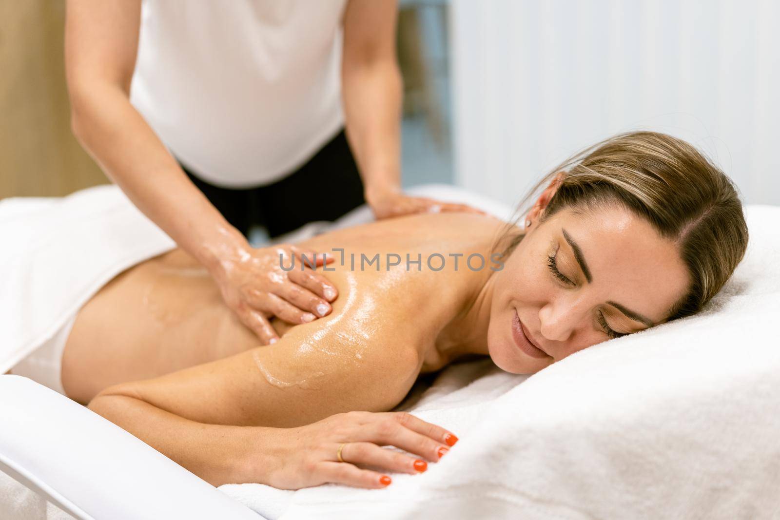 Woman receiving a back massage with massage candle oil. Body care treatment in a beauty centre.