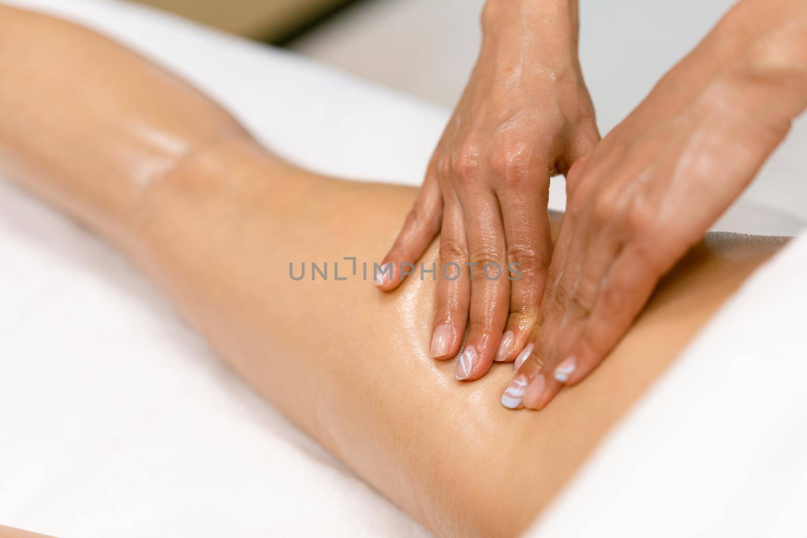 Beauty salon professional pouring oil from a massage candle on the back of his patient. by javiindy