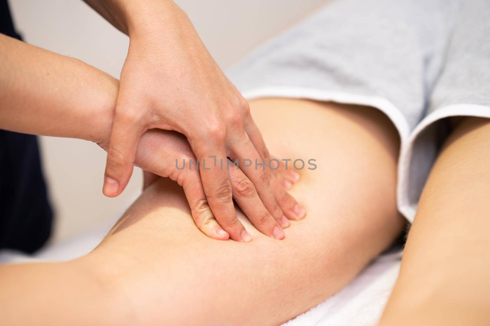 Medical massage at the leg in a physiotherapy center. Female physiotherapist inspecting her patient.