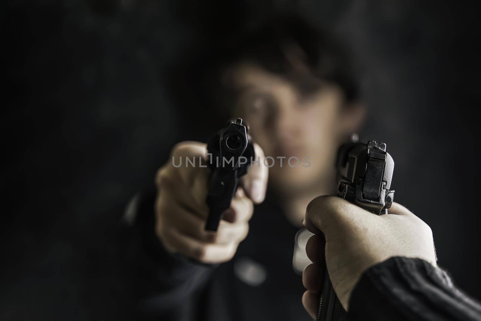Two men point pistols at each other. Threat to life. Close-up of hand with weapon. Shootout of criminals with revolvers. Dark background and dangerous situation. Killer or murderer.