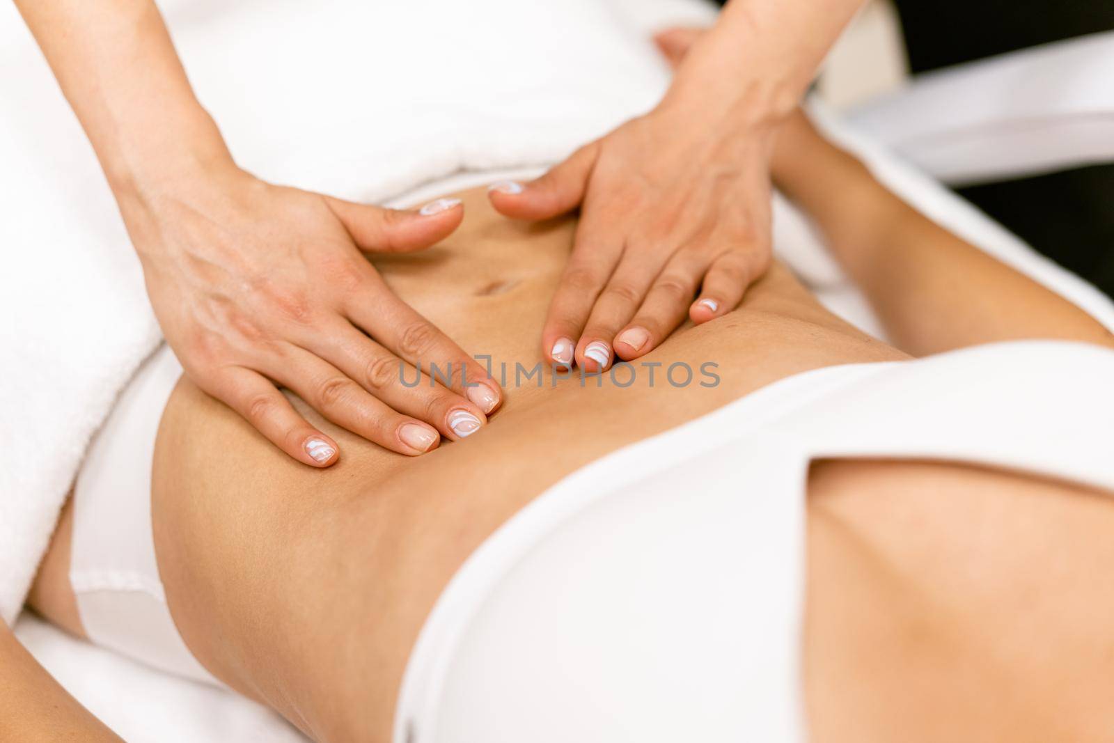 Middle-aged woman having a belly massage in a beauty salon. Body care treatment in a beauty centre.