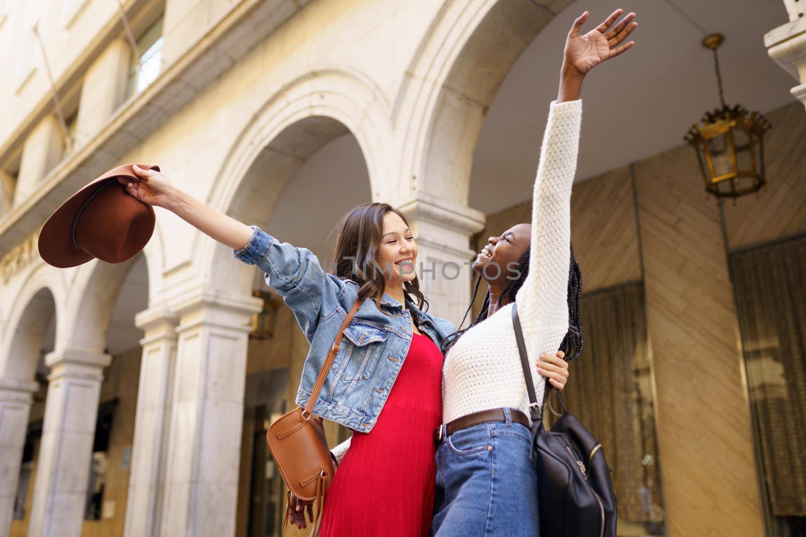 Two friends happy to see each other on the street hugging. Multiethnic women.